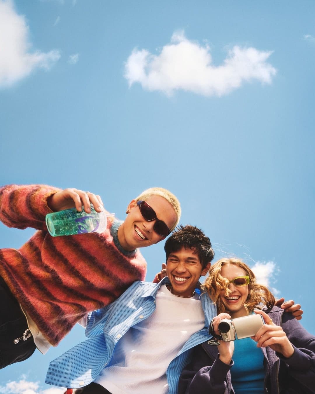Tres amigos filmando juntos bajo un cielo azul